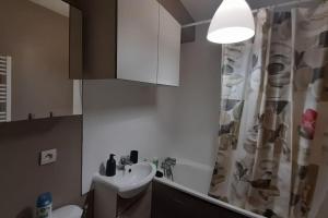 a bathroom with a sink and a shower curtain at Au pied de la Gare de Cergy le haut, centre villes in Cergy