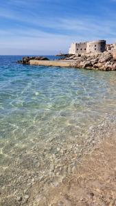 a beach with clear water and a building in the background at Atelier Tina Art Home in Dubrovnik