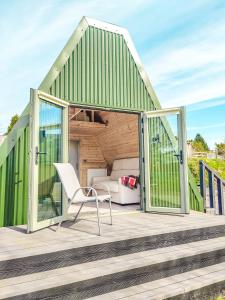 uma casa verde com uma cadeira branca num deque em Bective Mill Glamping & Camping 