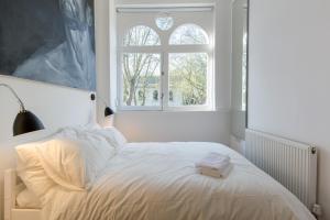 een wit bed in een kamer met een raam bij St. Lukes View, Shoreditch, by the Design Traveller in Londen