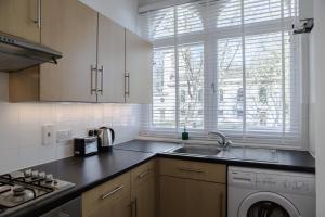 uma cozinha com um lavatório e uma máquina de lavar louça em St. Lukes View, Shoreditch, by the Design Traveller em Londres