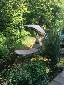 a bench with an umbrella in a garden at Chambre d'hôtes chez Denis et Margot in Chiré-en-Montreuil