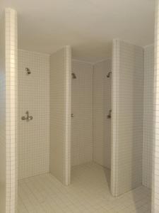 a white tiled bathroom with two shower stalls at Apartmany JaJ-Bavorsko in Mitterfirmiansreut