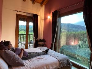 a woman laying on a bed in a room with a window at Casa Angiz etxea in Sumbilla