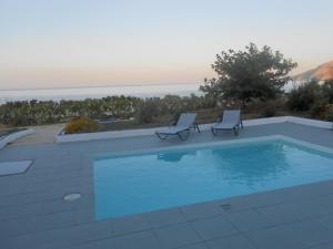 ein Pool mit zwei Liegestühlen daneben in der Unterkunft Grand Villa Lino in Skyros