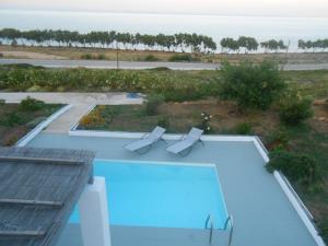 a swimming pool with two chairs and a view of the ocean at Grand Villa Lino in Skiros
