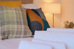 ein Bett mit Kissen und Lampe schließen in der Unterkunft Causey Lodge superb comfy home in Exeter by StayStay in Exeter