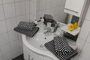 een badkamer met een wastafel en zwarte en witte handdoeken bij Nanninga Ferienwohnung Nanni 
