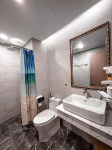 La salle de bains est pourvue de toilettes, d'un lavabo et d'un miroir. dans l'établissement FLC Tower Quy Nhon Abogo, à Quy Nhơn