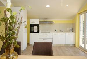 a kitchen with white cabinets and a table with a plant at Villa Tea in Donje Polje