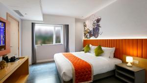 a bedroom with a large bed with an orange headboard at Hotel City Keys By Rivido, Electronic City in Bangalore