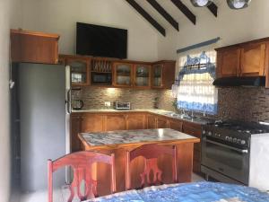 uma cozinha com armários de madeira e uma mesa com cadeiras em Bay View Apartments Canouan Island em Canouan