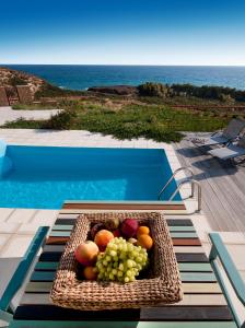 uma cesta de frutas sobre uma mesa ao lado de uma piscina em Villa Lino em Skiros