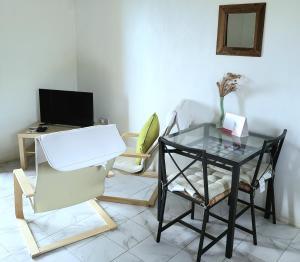 uma sala de estar com uma mesa de vidro e uma cadeira em Bay View Apartments Canouan Island em Canouan