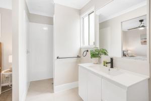 een witte badkamer met een wastafel en een spiegel bij Fraser Island Beach Houses in Fraser Island