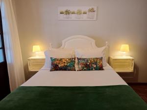 a bedroom with a white bed with two lamps at São Miguel do Gerês in Geres