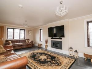 a living room with leather furniture and a flat screen tv at Mill End in Penrith
