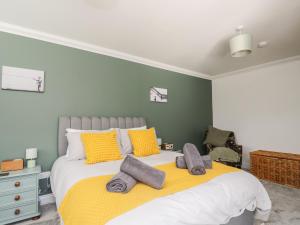 a bedroom with a large bed with yellow and gray pillows at Mill End in Penrith