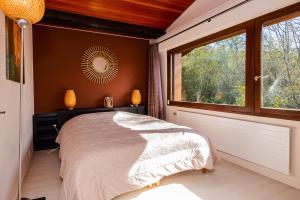 um quarto com uma cama e uma grande janela em Maison avec Piscine et Spa em Saint-Jean-dʼArvey