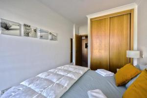 a bedroom with a large white bed with yellow pillows at Apartamento Varandas do Mar in Albufeira