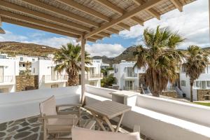 een balkon met een tafel en stoelen en palmbomen bij Ninemia Suites Tinos Superior 201 in Kionia