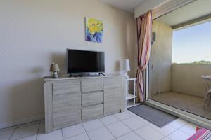 salon z telewizorem na komodzie w obiekcie Appartement clim piscine garage w mieście Le Grau-du-Roi