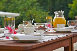 einen Holztisch mit Tellern und Weingläsern darauf in der Unterkunft Edenbrook Country Manor in Plettenberg Bay