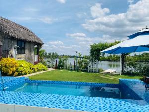 a swimming pool with an umbrella next to a house at The River Home in Nhơn Trạch