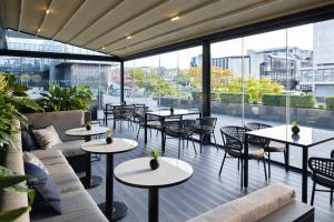 ein Restaurant mit Tischen und Stühlen und großen Fenstern in der Unterkunft Maistra City Vibes Hotel International in Zagreb