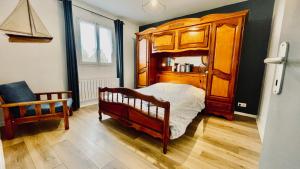 1 dormitorio con cama de madera y silla en Maison spacieuse à deux pas de la plage, en Roscanvel