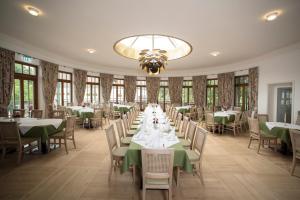 a dining room with tables and chairs and a chandelier at Gutshotel Odelzhausen in Odelzhausen