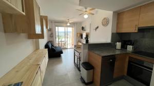 uma cozinha com armários de madeira e uma bancada em Apartamento acogedor con piscina en Santa Margarita em Roses