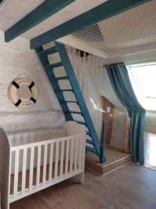 a room with a crib and a blue stair case at Gîte Le Cabestan à la mer Lingreville in Lingreville