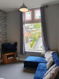 een woonkamer met een blauwe bank en een raam bij Central Matlock Apartment in Matlock