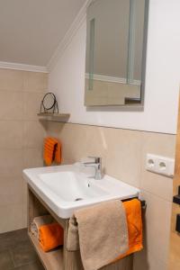 a bathroom with a white sink and orange towels at Dorfleben Embach in Embach