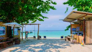 a beach with chairs and an umbrella and the ocean at Lipe Garden Beach Resort in Ko Lipe