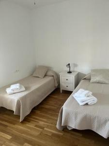 een slaapkamer met 2 bedden en een dressoir met handdoeken bij ático con terraza- solarium in Écija
