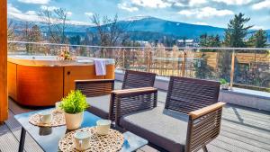Un balcón con 2 sillas y una bañera en una terraza. en Apartamenty z basenem ROYAL APARTS VIP Stone Hill Centrum z jacuzzi i saunami - widokowe, en Szklarska Poręba