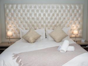 um quarto com uma grande cama branca e 2 candeeiros em Barkly Street Guesthouse em Uitenhage