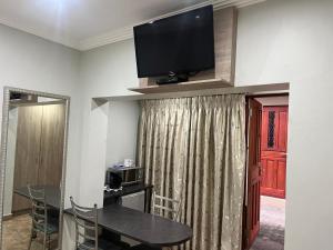 a dining room with a table and a television on a wall at Barkly Street Guesthouse in Uitenhage
