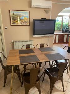 a dining room table with chairs and a flat screen tv at Apartments Oliva in Poreč