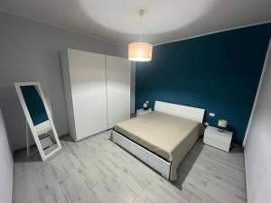 1 dormitorio con cama y pared azul en Amare Home, en Porto Cesareo