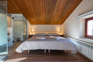 a bedroom with a large bed with a wooden ceiling at Masía El Pinatell in Castellar del Riu