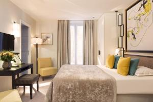 パリにあるバルモラル シャンゼリゼのベッド、デスク、椅子が備わるホテルルームです。