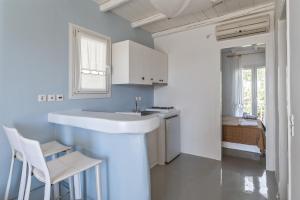 a white kitchen with a sink and a table at Ninemia Suites Tinos Grand 104 in Kionia +14 photos