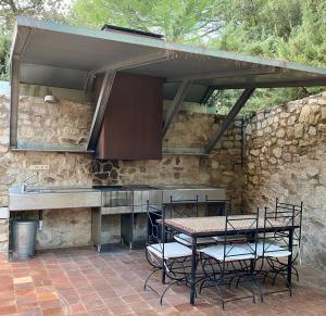 un patio con mesa, sillas y pared de piedra. en Luxury home Paraiso with pool and gym en Valdemorillo