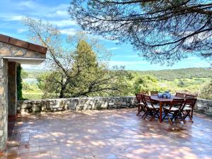 un patio con mesa, sillas y pared de piedra. en Luxury home Paraiso with pool and gym en Valdemorillo