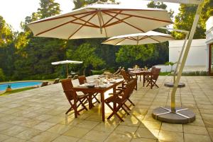 a patio with tables and umbrellas next to a pool at Edenbrook Country Manor in Plettenberg Bay +38 photos