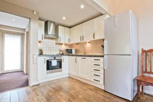 a kitchen with white cabinets and a refrigerator at The Bridge Hotel Self Catering in Buttermere