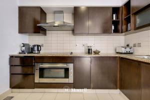 a kitchen with stainless steel appliances and brown cabinets at Manzil - Lavish 3BR resort with private beach at Tiara Residence Palm Jumeirah in Dubai